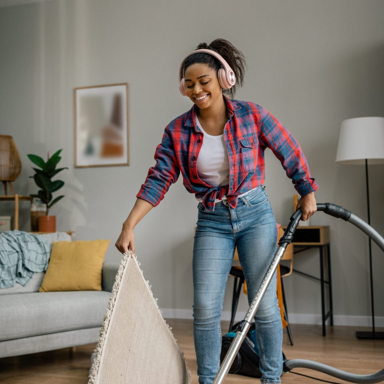 Cheerful,Young,Black,Female,In,Wireless,Headphones,With,Vacuum,Cleaner